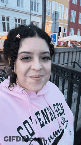 A Woman Wearing A Pink Hoodie That Says Copenhagen On It GIF