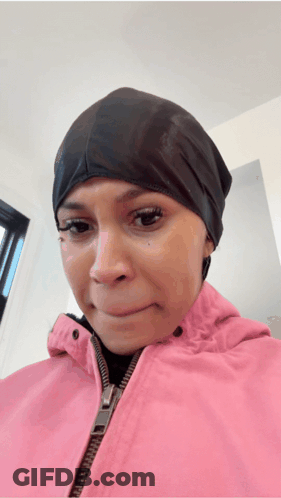 A Woman Wearing A Pink Jacket And A Black Hat Is Making A Sad Face GIF