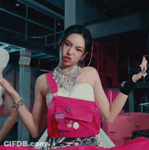 A Woman Wearing A Pink Overalls And A Necklace With A Button That Says Adb GIF
