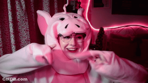 A Woman Wearing A Pink Pig Costume And Glasses Is Smiling . GIF