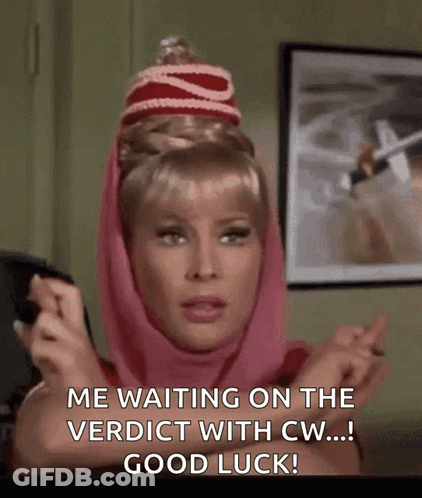 A Woman Wearing A Pink Scarf And A Red Hat Is Waiting On The Verdict With Good Luck . GIF