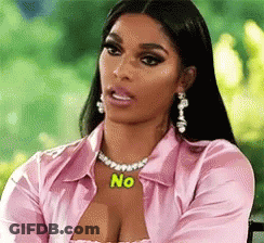 A Woman Wearing A Pink Shirt And A Necklace With The Word No On It Is Sitting In A Chair . GIF