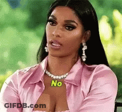 A Woman Wearing A Pink Shirt And A Necklace With The Word No On It Is Sitting On A Chair . GIF
