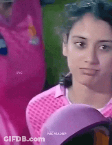 A Woman Wearing A Pink Shirt And A Purple Hat Is Looking At The Camera . GIF