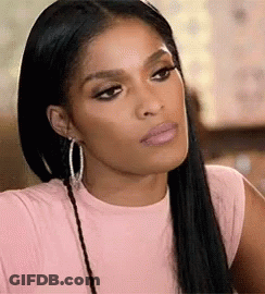A Woman Wearing A Pink Shirt And Hoop Earrings Is Making A Serious Face . GIF