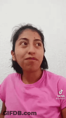 A Woman Wearing A Pink Shirt Is Making A Funny Face . GIF