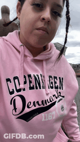 A Woman Wearing A Pink Sweatshirt That Says Copenhagen Denmark GIF