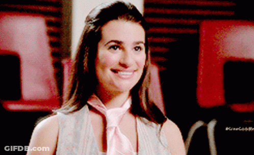 A Woman Wearing A Pink Tie Is Smiling And Looking At The Camera GIF