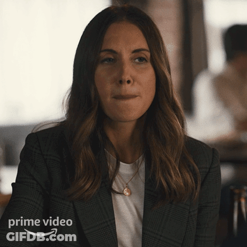 A Woman Wearing A Plaid Jacket Is Sitting In Front Of A Prime Video Ad GIF