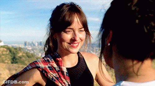 A Woman Wearing A Plaid Scarf Is Smiling At Another Woman GIF