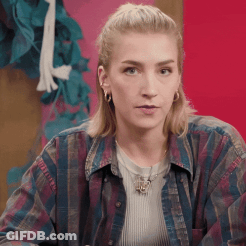 A Woman Wearing A Plaid Shirt And A Necklace With A Pendant That Says ' A ' On It GIF