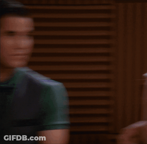 A Woman Wearing A Plaid Shirt And A Scarf Looks At The Camera GIF