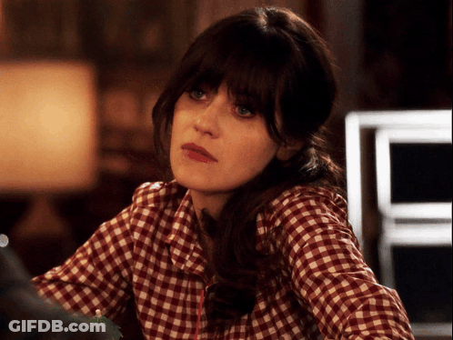 A Woman Wearing A Plaid Shirt Is Looking At Something GIF