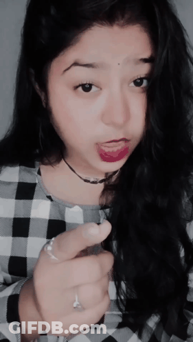 A Woman Wearing A Plaid Shirt Is Making A Face GIF