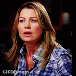 A Woman Wearing A Plaid Shirt Is Making A Surprised Face . GIF