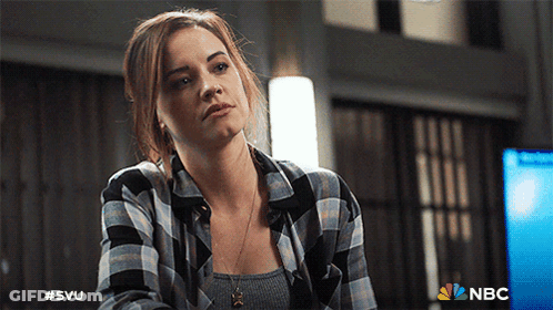 A Woman Wearing A Plaid Shirt Is Sitting In Front Of A Nbc Logo GIF