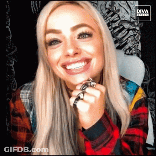 A Woman Wearing A Plaid Shirt Is Smiling With The Diva Girls Logo Behind Her GIF