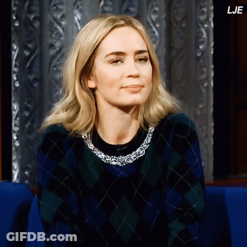 A Woman Wearing A Plaid Sweater Is Sitting In A Blue Chair And The Letters Lje Are On The Bottom Right GIF