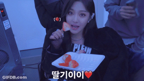 A Woman Wearing A Plein Sweatshirt Eating Strawberries GIF