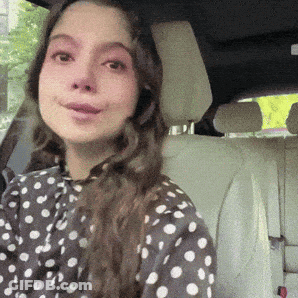 A Woman Wearing A Polka Dot Shirt Is Sitting In The Back Seat Of A Car GIF