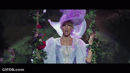 A Woman Wearing A Purple Hat And A White Dress Is Standing On A Swing GIF