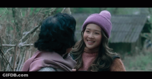 A Woman Wearing A Purple Hat Is Smiling At Another Woman In A Pink Sweater GIF