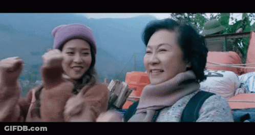 A Woman Wearing A Purple Hat Is Standing Next To An Older Woman Wearing A Sweater And Scarf . GIF