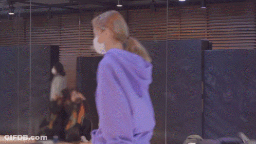 A Woman Wearing A Purple Hoodie And A Bandana Is Standing In A Room . GIF