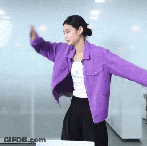 A Woman Wearing A Purple Jacket And A White Tank Top Is Dancing . GIF