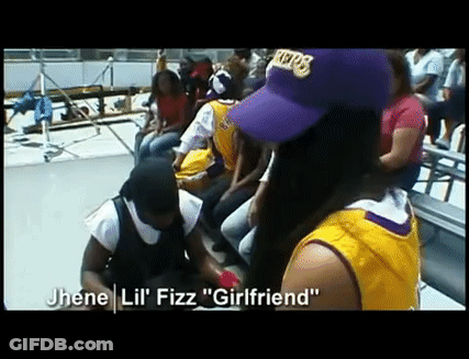 A Woman Wearing A Purple Lakers Hat Sits In A Crowd Of People GIF