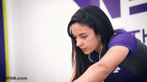 A Woman Wearing A Purple Shirt With The Letter W On The Front GIF
