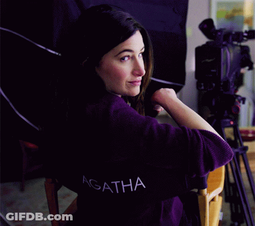 A Woman Wearing A Purple Shirt With The Word Agatha On The Back GIF