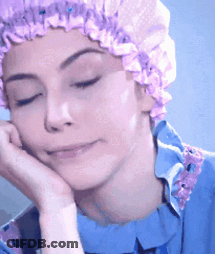 A Woman Wearing A Purple Shower Cap Rests Her Hand On Her Face GIF