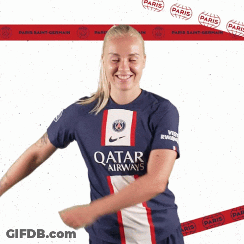 A Woman Wearing A Qatar Airways Shirt Stands In Front Of A Paris Saint-Germain Banner GIF