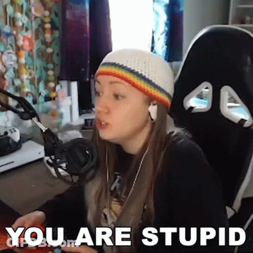 A Woman Wearing A Rainbow Hat And Headphones Is Sitting In Front Of A Computer With The Words " You Are Stupid " Above H GIF