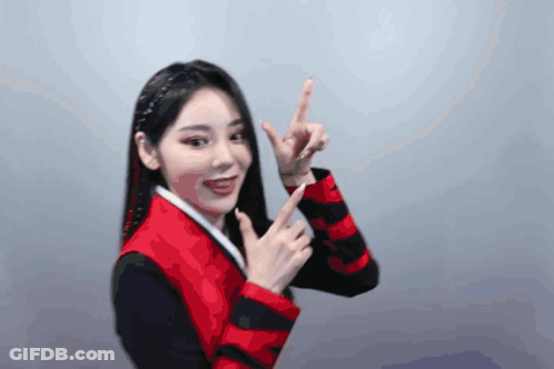 A Woman Wearing A Red And Black Jacket Is Pointing Up GIF