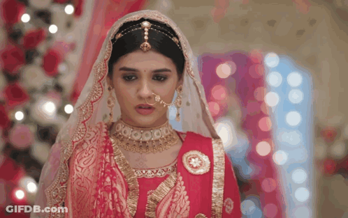 A Woman Wearing A Red And Gold Dress And Veil GIF