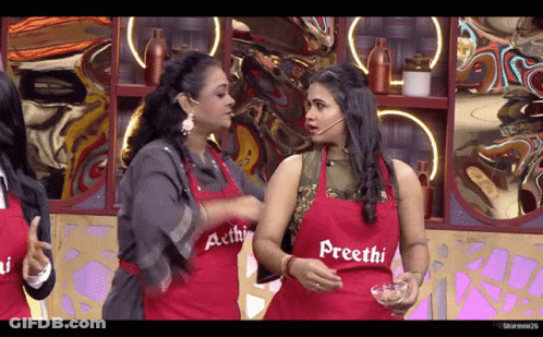 A Woman Wearing A Red Apron That Says Precthi Talks To Another Woman GIF