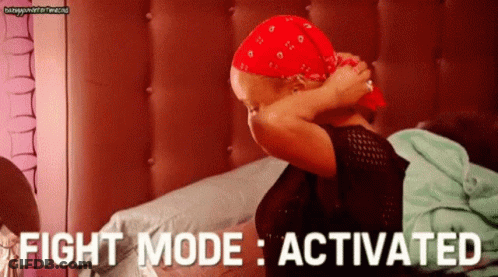 A Woman Wearing A Red Bandana Is Sitting On A Bed With The Words Fight Mode Activated . GIF
