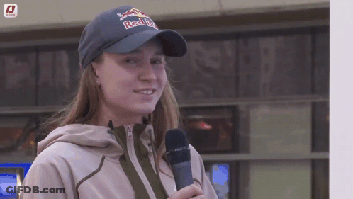 A Woman Wearing A Red Bull Hat Holds A Microphone In Her Hand GIF