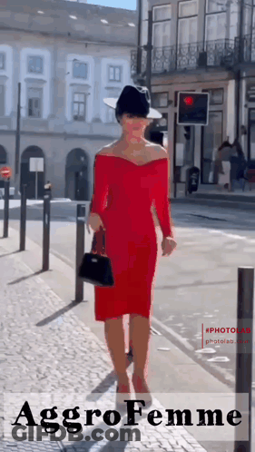 Woman In Red Dress And Black Hat Walking Down Street GIF