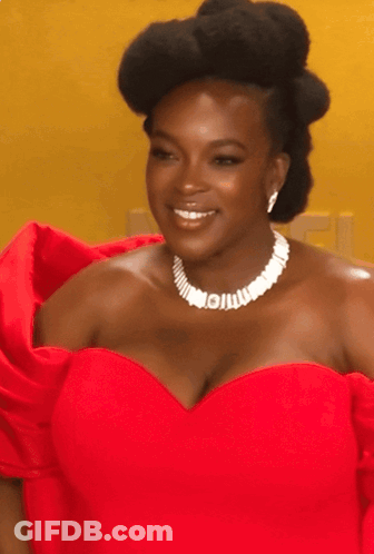 A Woman Wearing A Red Dress And A White Necklace With The Letter I On It GIF