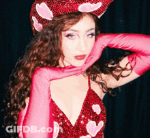 A Woman Wearing A Red Dress And Pink Gloves With Hearts On Them GIF