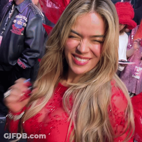 A Woman Wearing A Red Dress Is Smiling And Making A Funny Face . GIF