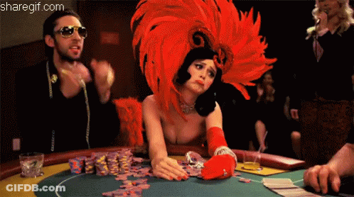 A Woman Wearing A Red Feathered Headdress Is Playing Poker GIF
