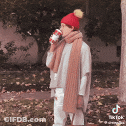 A Woman Wearing A Red Hat And Scarf Is Drinking A Cup Of Coffee GIF