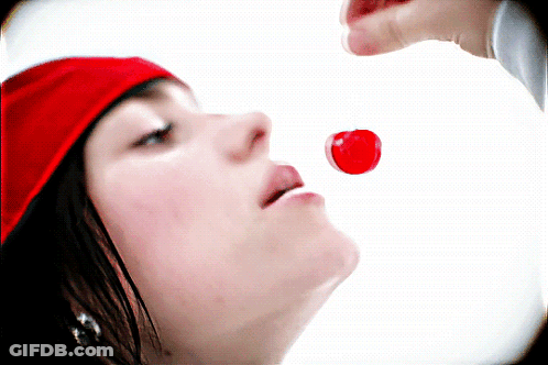 A Woman Wearing A Red Hat Is Eating A Red Candy GIF
