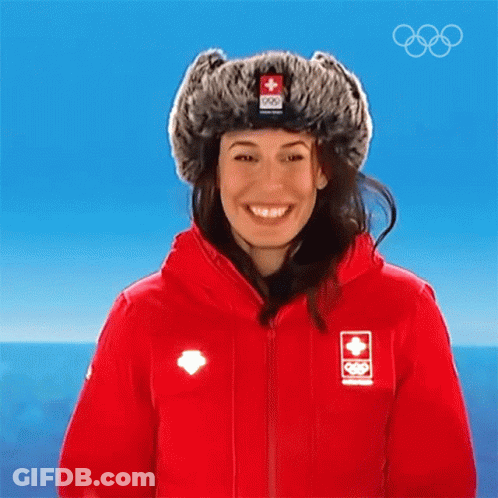 A Woman Wearing A Red Jacket And A Fur Hat With A Swiss Flag On It GIF