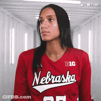 A Woman Wearing A Red Nebraska Jersey Looks To The Side GIF