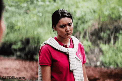 A Woman Wearing A Red Polo Shirt And A White Sweater Around Her Neck Is Making A Funny Face . GIF